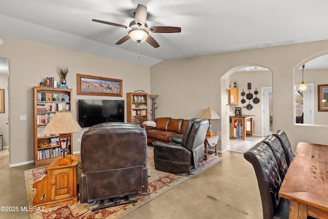 living area featuring vaulted ceiling, baseboards, arched walkways, and ceiling fan