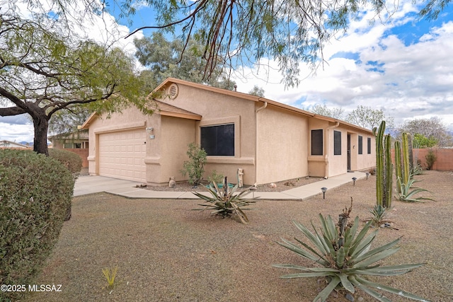 view of front of home with stucco siding, driveway, an attached garage, and fence