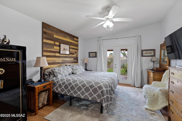 bedroom with access to exterior, wood finished floors, french doors, wooden walls, and ceiling fan