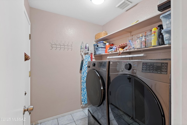 washroom featuring baseboards, visible vents, laundry area, tile patterned floors, and washer and clothes dryer