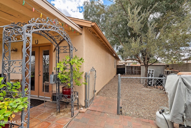 view of home's exterior featuring a patio, a fenced backyard, stucco siding, an outdoor structure, and french doors