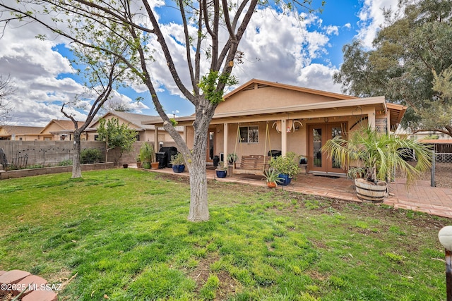 back of property with stucco siding, a patio, a lawn, and fence