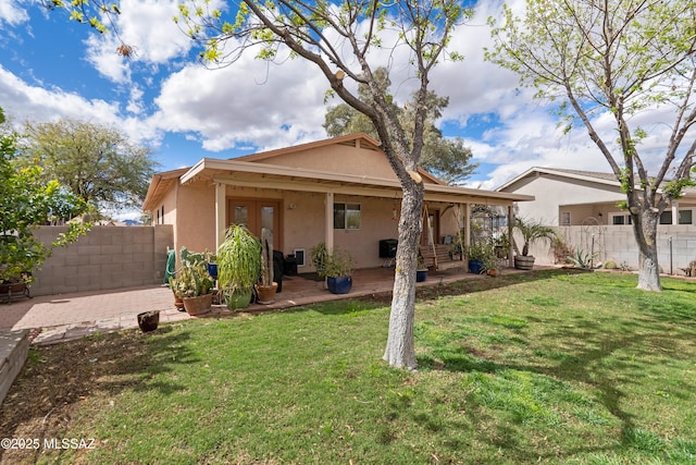 rear view of property featuring stucco siding, a yard, and fence