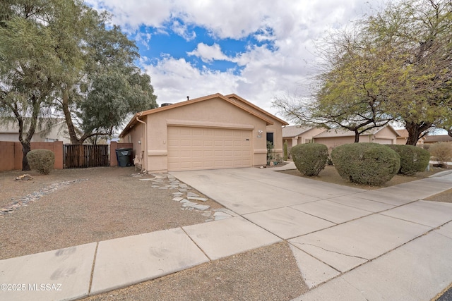 view of front facade featuring a gate, fence, stucco siding, concrete driveway, and a garage