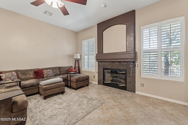 tiled living room featuring visible vents, baseboards, ceiling fan, and a tile fireplace