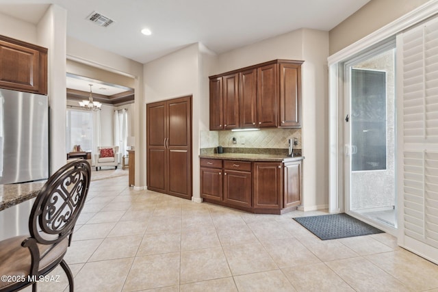 kitchen featuring a notable chandelier, visible vents, freestanding refrigerator, and light tile patterned floors