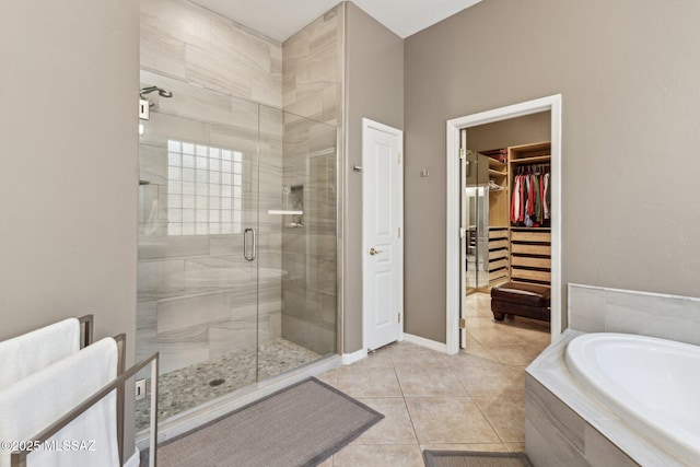 full bath featuring a garden tub, a shower stall, tile patterned flooring, baseboards, and a spacious closet