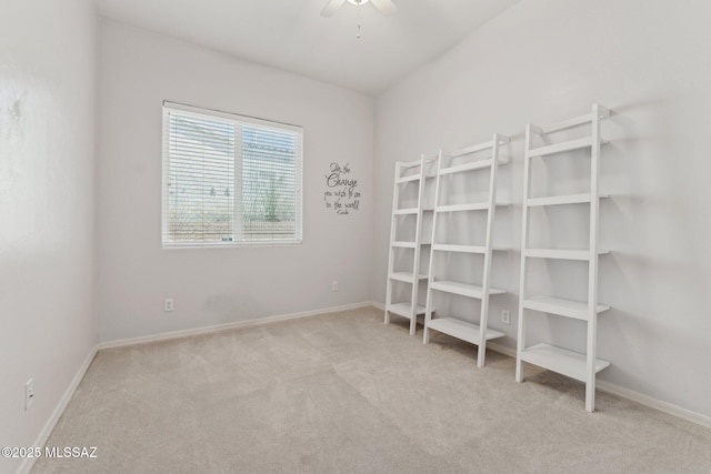 carpeted spare room featuring baseboards and ceiling fan