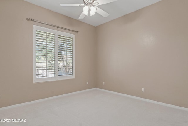 carpeted empty room featuring a ceiling fan and baseboards