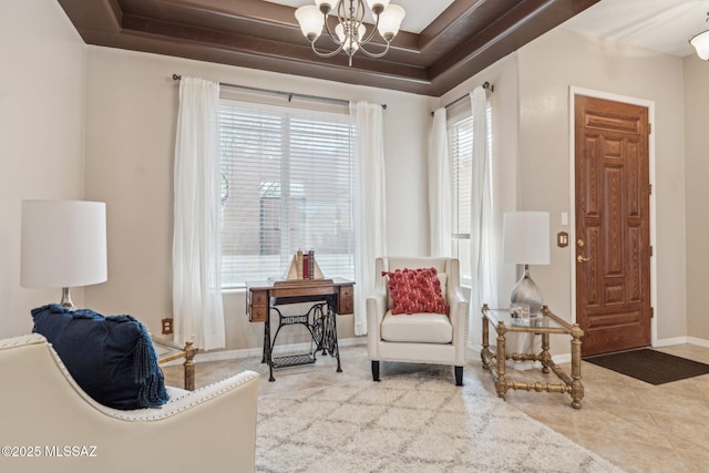 sitting room with an inviting chandelier, a raised ceiling, baseboards, and tile patterned flooring