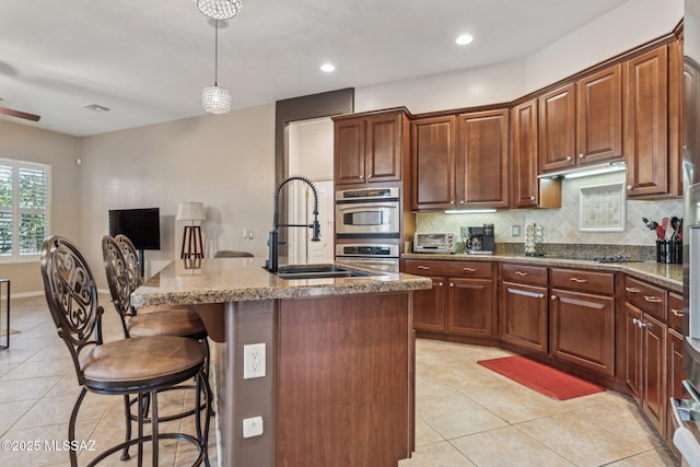 kitchen featuring light tile patterned floors, backsplash, stone countertops, and a sink