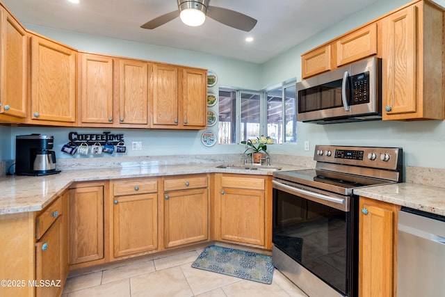 kitchen featuring light stone counters, light tile patterned flooring, appliances with stainless steel finishes, and a sink