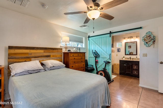 bedroom with a sink, visible vents, a barn door, and ensuite bath