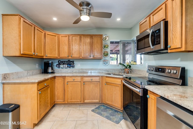 kitchen with a sink, light stone counters, light tile patterned floors, and stainless steel appliances