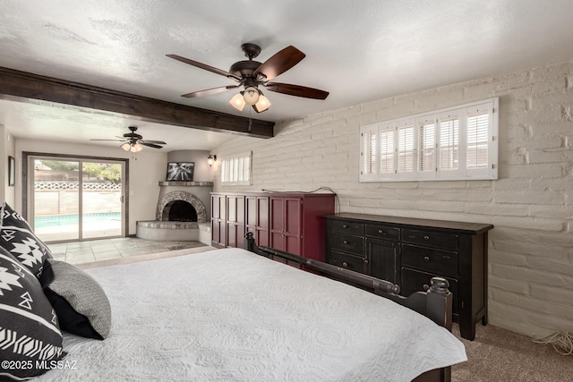 carpeted bedroom with a fireplace with raised hearth, multiple windows, a textured ceiling, and access to outside