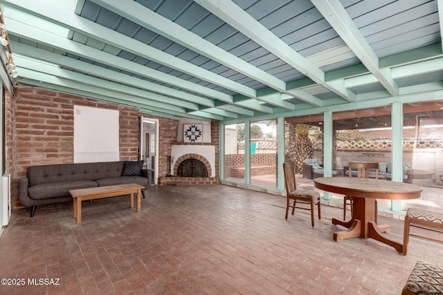 sunroom with a brick fireplace and lofted ceiling with beams