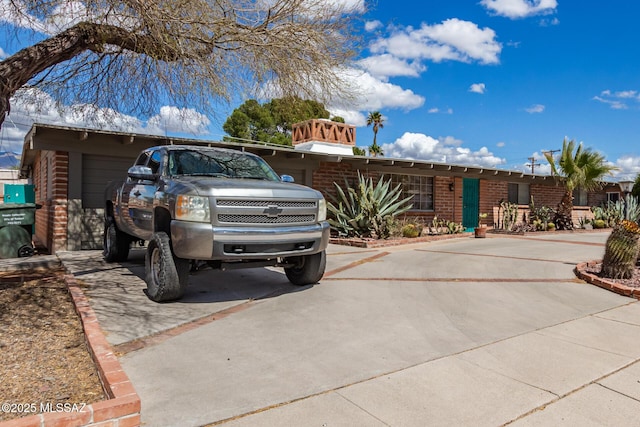 single story home with a garage, brick siding, and driveway