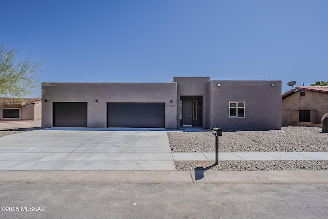 pueblo-style house featuring stucco siding, concrete driveway, and an attached garage