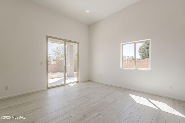 spare room with a wealth of natural light, baseboards, and light wood-style flooring