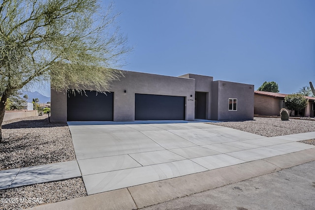 pueblo revival-style home featuring stucco siding, concrete driveway, and an attached garage