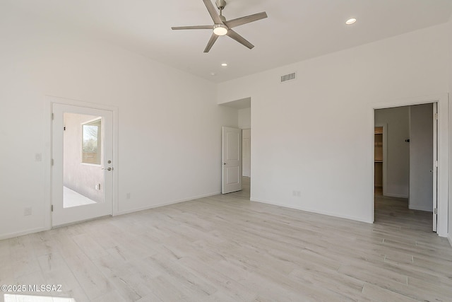 unfurnished room featuring a ceiling fan, visible vents, light wood finished floors, recessed lighting, and a towering ceiling