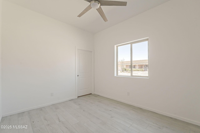 spare room featuring ceiling fan, baseboards, and light wood-style floors