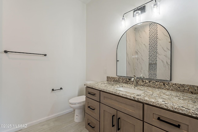 bathroom featuring baseboards, toilet, wood finished floors, and vanity