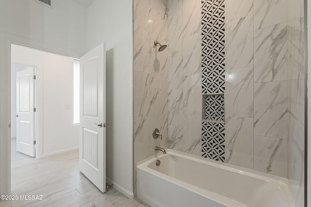 bathroom featuring tub / shower combination, baseboards, and wood finish floors