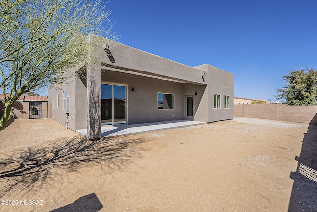 rear view of property featuring stucco siding, a patio, and a fenced backyard