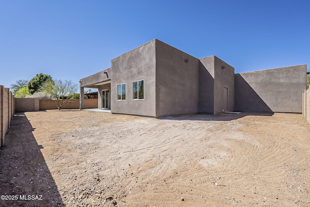 back of house with stucco siding and a fenced backyard