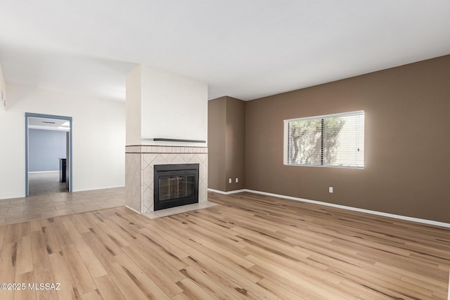 unfurnished living room featuring baseboards, light wood-style flooring, and a fireplace