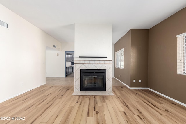 unfurnished living room featuring baseboards, wood finished floors, and a fireplace