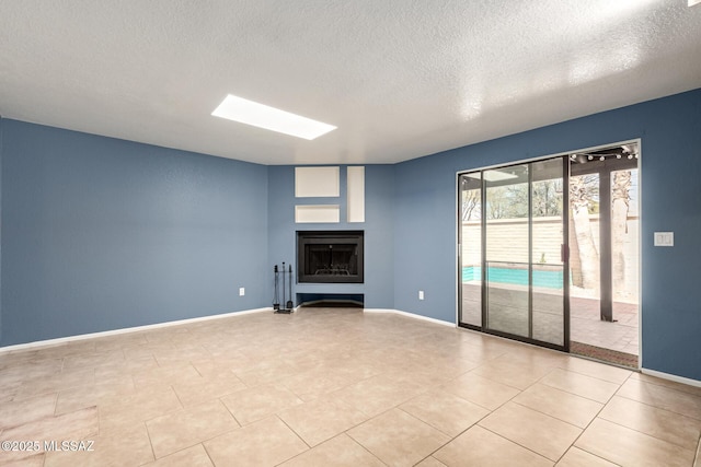 unfurnished living room featuring a fireplace, a skylight, and baseboards