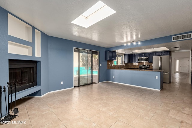 unfurnished living room featuring a sink, visible vents, baseboards, and a skylight