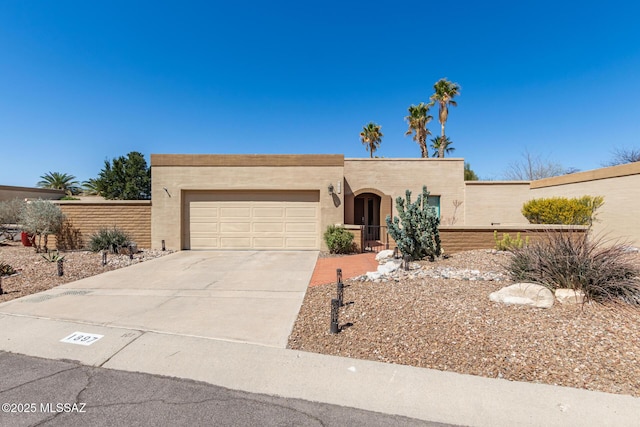 southwest-style home featuring stucco siding, an attached garage, and driveway