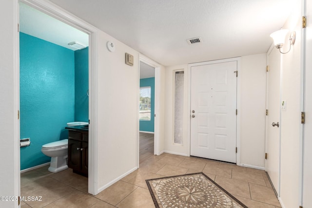 foyer entrance with light tile patterned floors, visible vents, and baseboards