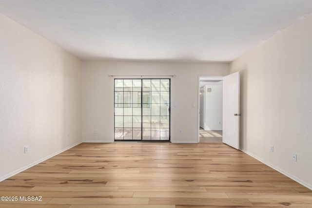 empty room featuring baseboards and light wood-style flooring