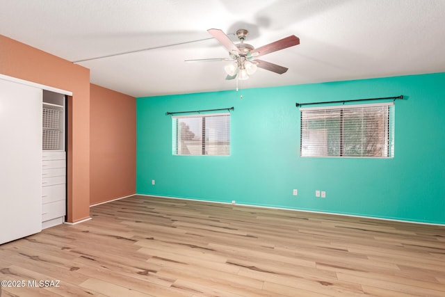 unfurnished bedroom featuring a closet, baseboards, a ceiling fan, and wood finished floors