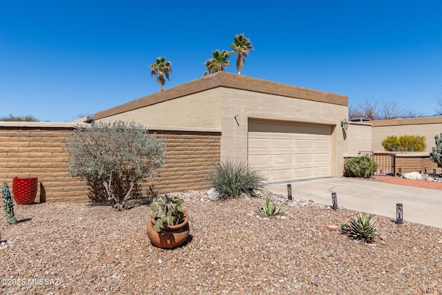 view of front facade featuring an attached garage, concrete driveway, and fence