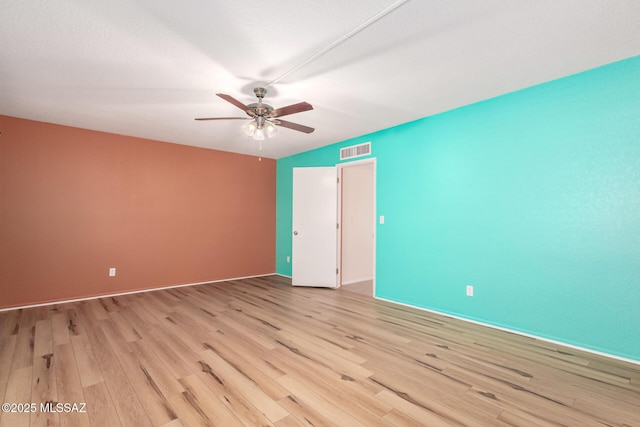 empty room featuring visible vents, light wood-style flooring, and a ceiling fan