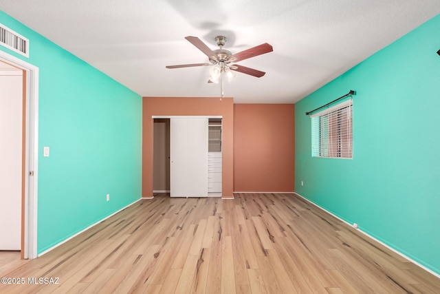 unfurnished bedroom featuring visible vents, wood finished floors, a closet, baseboards, and ceiling fan