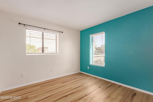 empty room featuring baseboards, a healthy amount of sunlight, and wood finished floors