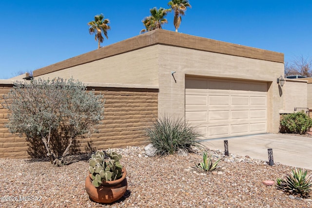 view of side of home featuring stucco siding, driveway, and an attached garage