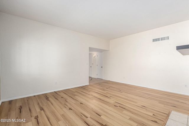 spare room featuring baseboards, visible vents, and light wood finished floors