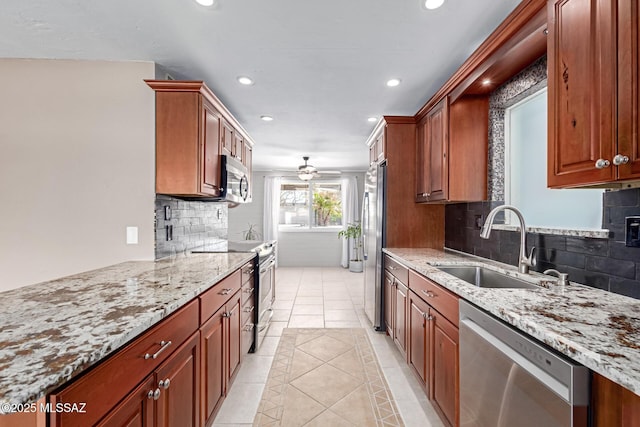 kitchen with light tile patterned floors, light stone countertops, recessed lighting, a sink, and appliances with stainless steel finishes