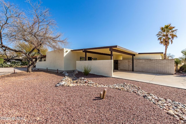 exterior space with a carport, stucco siding, driveway, and fence