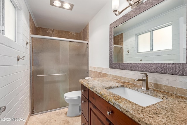 bathroom featuring vanity, a shower stall, toilet, and tile walls