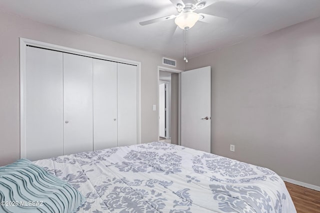 bedroom featuring visible vents, wood finished floors, a closet, baseboards, and ceiling fan