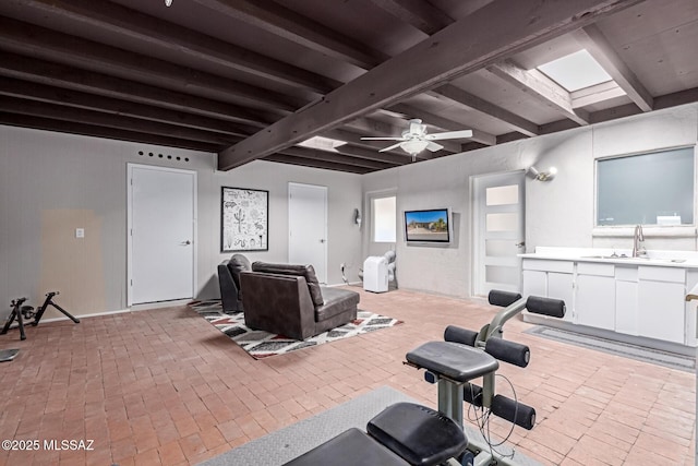 workout area with a skylight, a ceiling fan, brick floor, and a sink