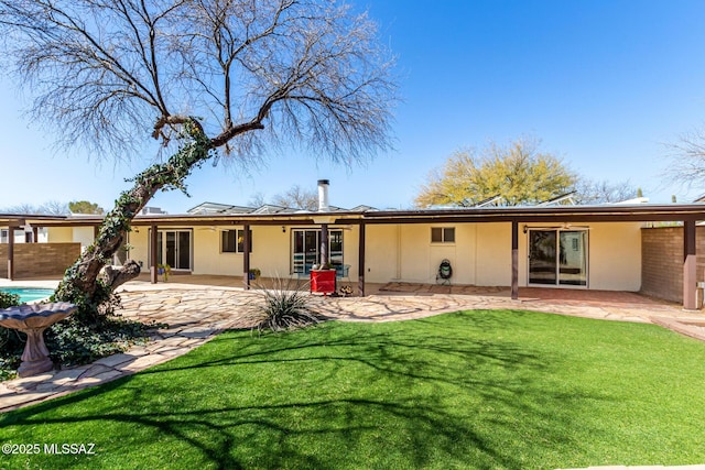 rear view of property featuring stucco siding, a lawn, and a patio area